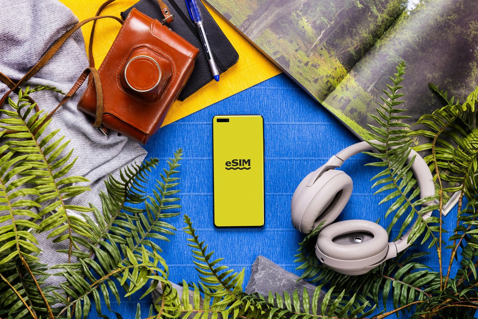 A book, headphones, a camera, and a cell phone on a table